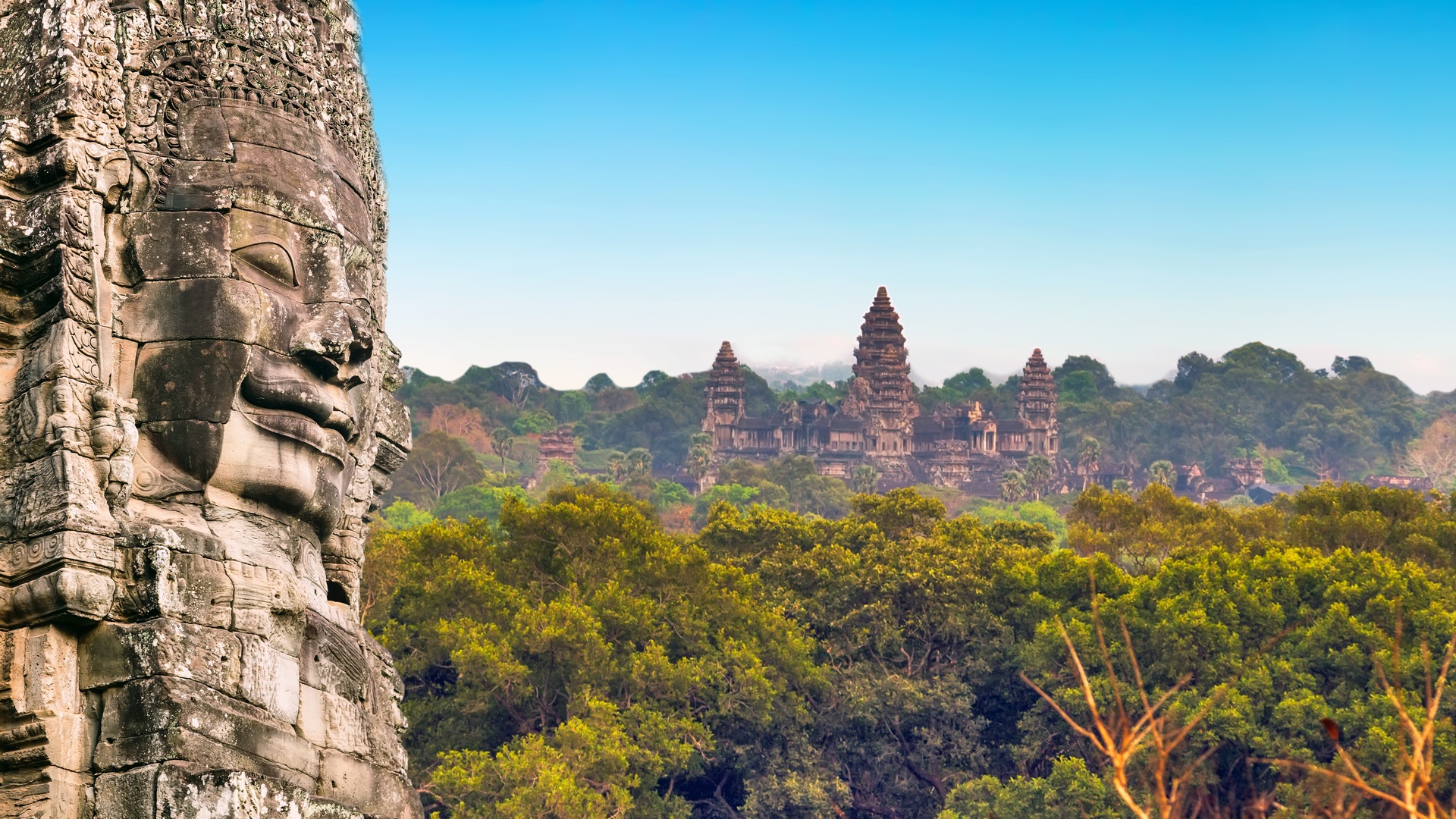 Stone face of Angkor Thom with Angkor Wat temple