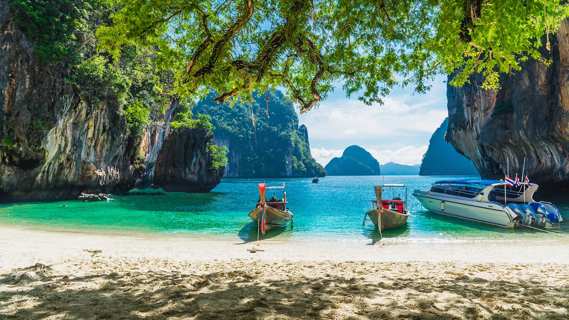 a scenic view of a beach in Thailand, featuring traditional Thai longtail boats and limestone cliffs