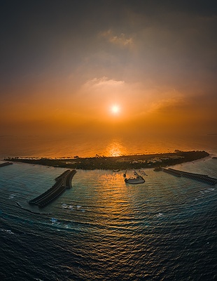 Aerial view of Siyam World Maldives at sunset with glowing ocean horizon
