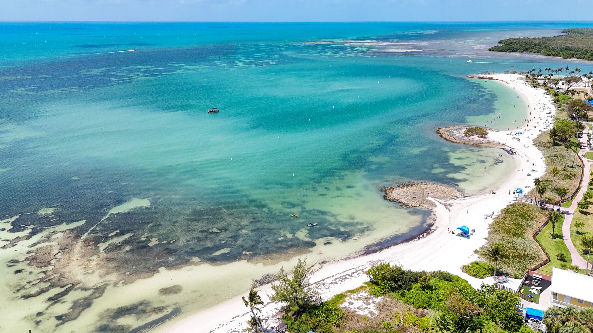 Aerial view of shallow turquoise sea and white sandy beach curving along the coast of Florida Keys