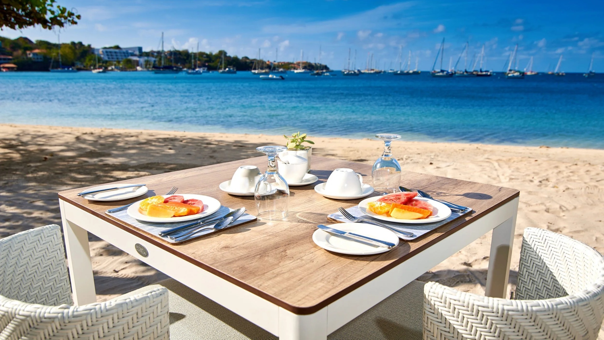 a breakfast setting directly on a white sand beach at the Calabash Hotel in Grenada