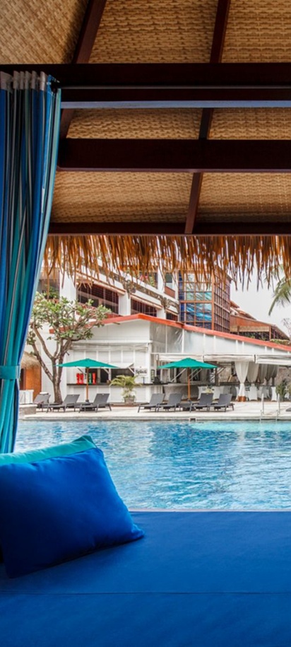 a poolside cabana overlooking the large sand-island swimming pool