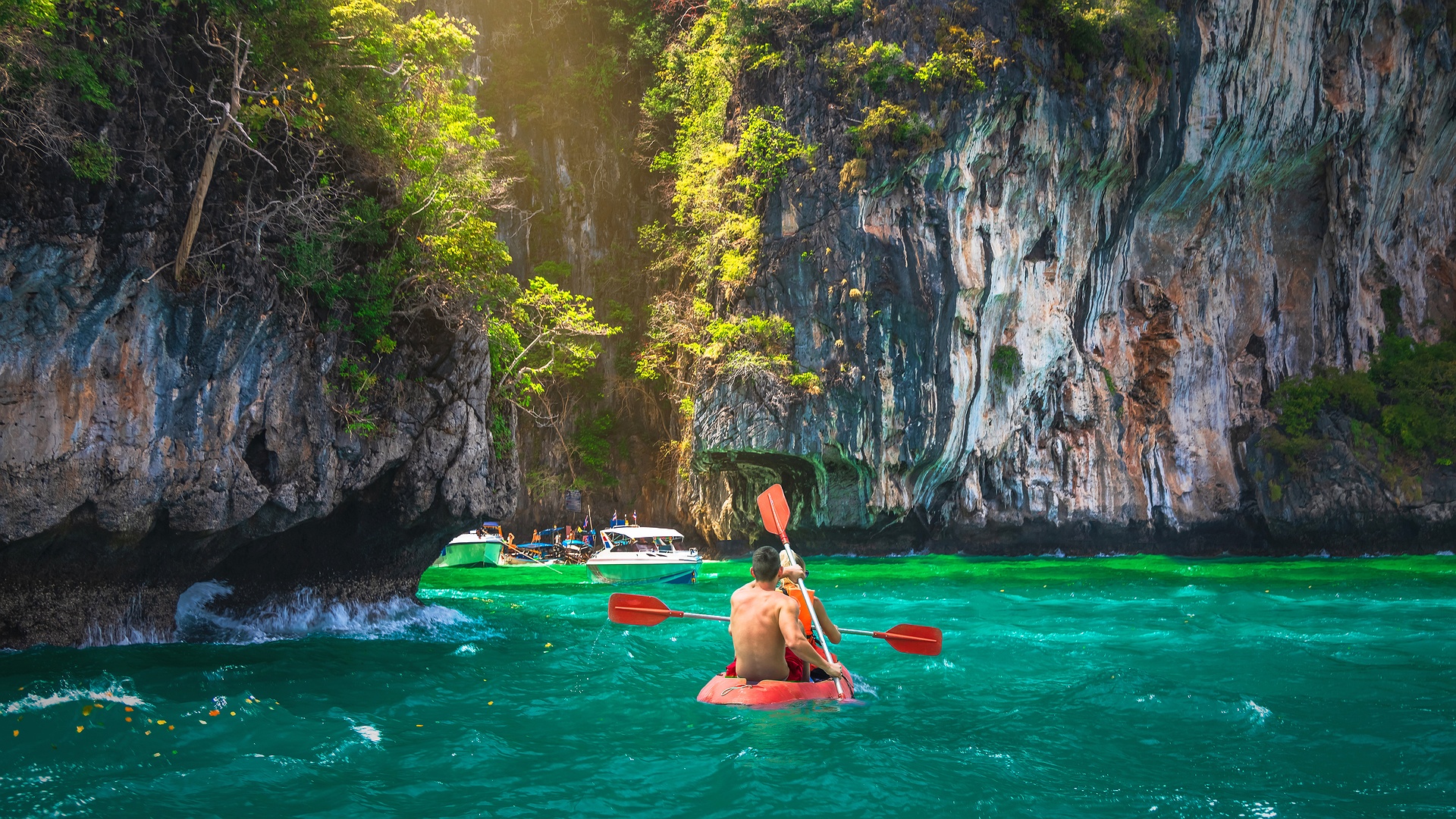 a tourist kayaking in the emerald waters of Pi Leh Lagoon, located within the Phi Phi Islands in Krabi, Thailand