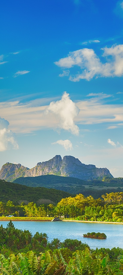 a scenic panorama of a lake surrounded by lush green forests and volcanic mountains on Mauritius island
