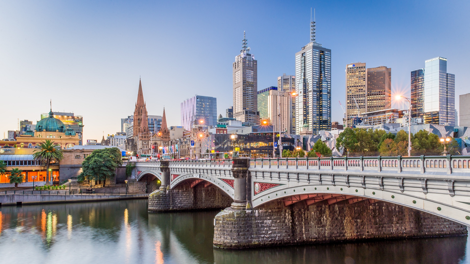 the cityscape of Melbourne, Australia, featuring the Yarra River and Princes Bridge at sunset