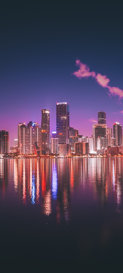 a tranquil nighttime view of the Miami skyline reflected on the calm waters of Biscayne Bay