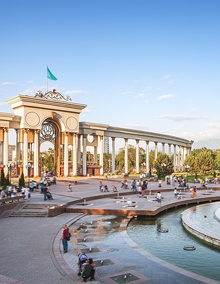 a nighttime panoramic view of Almaty, Kazakhstan, with the Zailiysky Alatau mountains in the background
