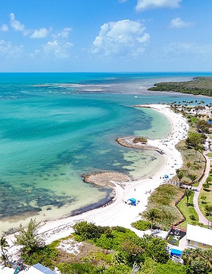 Aerial view of shallow turquoise sea and white sandy beach curving along the coast of Florida Keys
