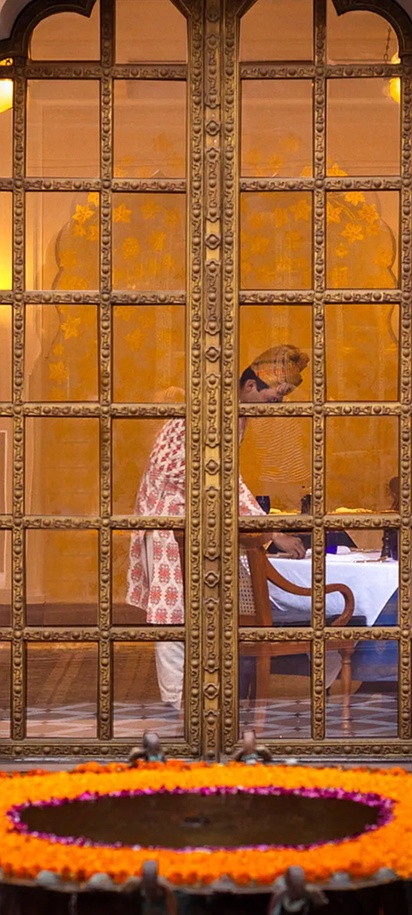 the traditional ornate glass-and-brass panel doors and pink-plastered archway entrance at The Oberoi Rajvilas, Jaipur