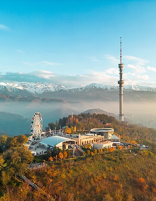 a nighttime panoramic view of Almaty, Kazakhstan, with the Zailiysky Alatau mountains in the background