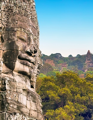 Stone face of Angkor Thom with Angkor Wat temple