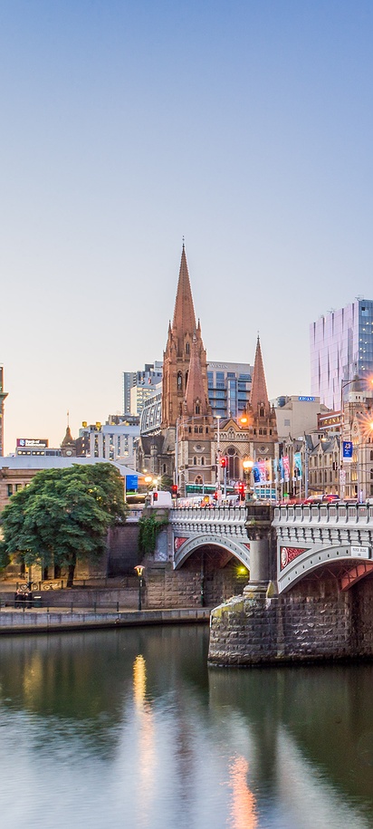 the cityscape of Melbourne, Australia, featuring the Yarra River and Princes Bridge at sunset